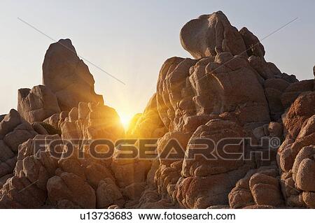 Stock Image - Sun shining through rock formations. Fotosearch