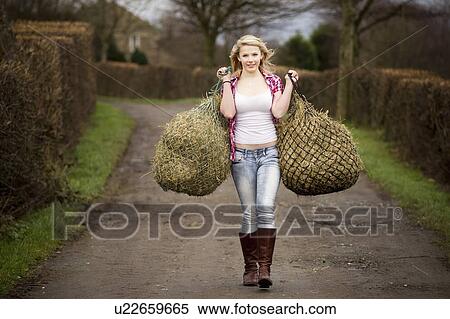 Teenage girl carrying hay on dirt path View Large Photo Image Stock Photography - Teenage girl carrying hay on dirt path. Fotosearch
