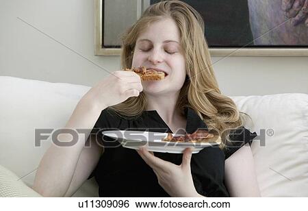 Teenage girl eating on sofa View Large Photo Image Stock Photograph - Teenage girl eating on sofa. Fotosearch