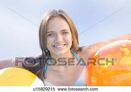 Stock Photography - Teenage girl in braces holding toys. Fotosearch
