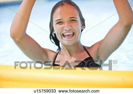 Stock Image - Teenage girl in braces playing in pool. Fotosearch