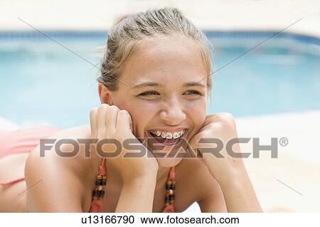 Stock Image - Teenage girl in braces relaxing by pool. Fotosearch