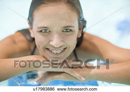 Teenage girl in braces relaxing in pool View Large Photo Image Stock Photograph - Teenage girl in braces relaxing in pool. Fotosearch