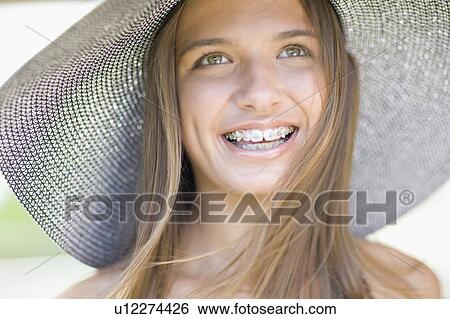 Stock Photograph - Teenage girl in braces wearing sunhat. Fotosearch