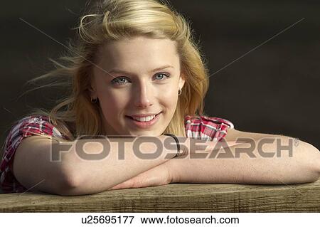 Stock Photo - Teenage girl leaning on wooden fence. Fotosearch