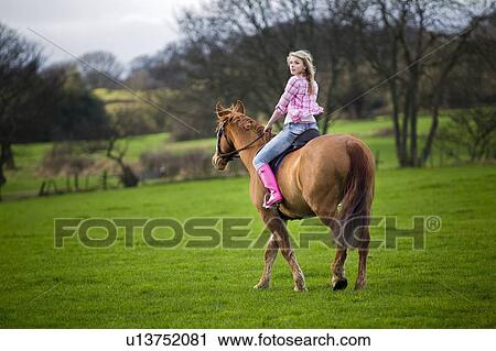 Teenage girl riding horse in field View Large Photo Image Stock Image - Teenage girl riding horse in field. Fotosearch