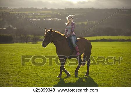 Teenage girl riding horse in field View Large Photo Image Stock Photo - Teenage girl riding horse in field. Fotosearch