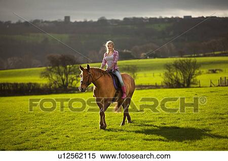 Stock Photography - Teenage girl riding horse in field. Fotosearch