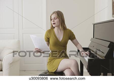 Stock Photograph - Teenage girl singing and playing piano. Fotosearch