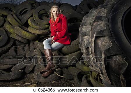 Stock Photography - Teenage girl sitting on discarded tires. Fotosearch
