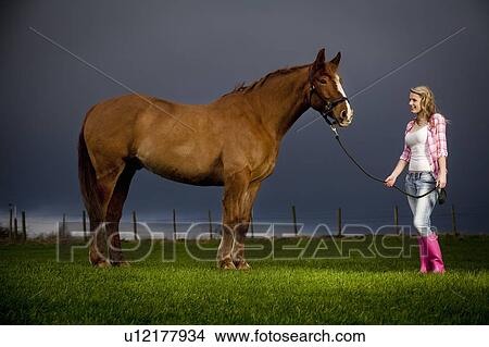 Picture - Teenage girl walking horse in field. Fotosearch