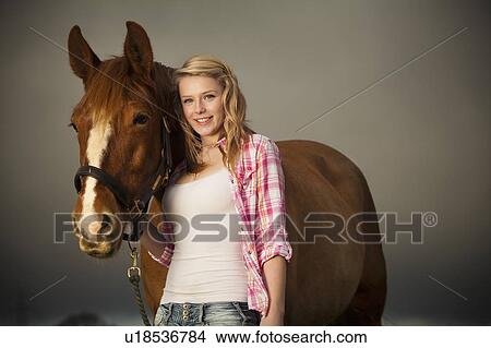 Picture - Teenage girl walking horse in field. Fotosearch