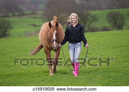 Stock Photo - Teenage girl walking horse in field. Fotosearch