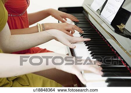 Picture - Teenage girls playing piano together. Fotosearch