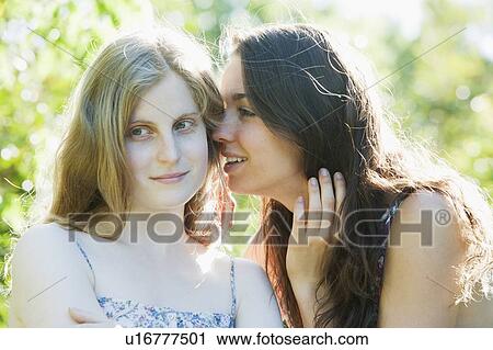 Stock Image - Teenage girls whispering outdoors. Fotosearch