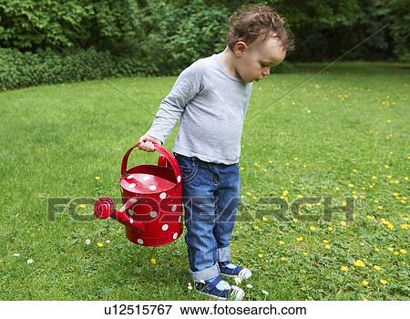 Toddler boy carrying watering can View Large Photo Image Stock Photo - Toddler boy carrying watering can. Fotosearch
