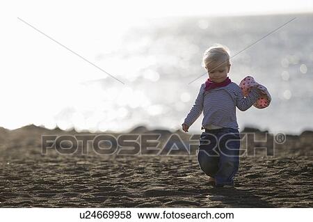 Toddler carrying sunhat on beach View Large Photo Image Stock Photo - Toddler carrying sunhat on beach. Fotosearch