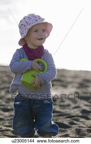 Toddler carrying watering can on beach View Large Photo Image Picture - Toddler carrying watering can on beach. Fotosearch