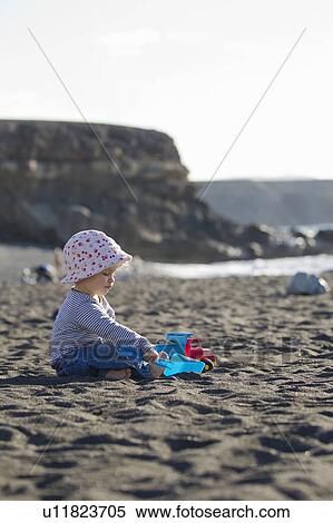 Stock Photography - Toddler playing with shovel on beach. Fotosearch