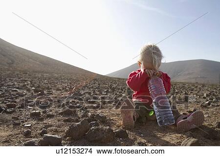 Picture - Toddler with bottle of water in desert. Fotosearch