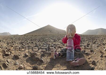 Picture - Toddler with bottle of water in desert. Fotosearch