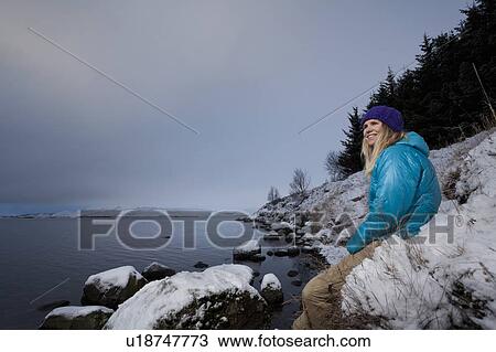 Stock Image - Woman admiring lake in snow. Fotosearch