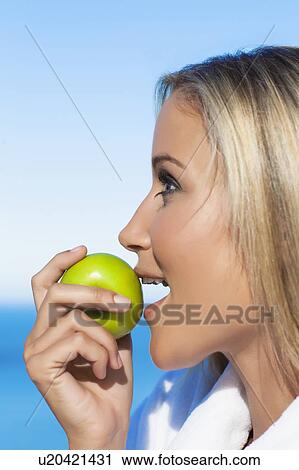 Stock Image - Woman biting apple outdoors. Fotosearch
