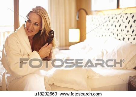 Woman brushing her hair on bed View Large Photo Image Stock Photo - Woman brushing her hair on bed. Fotosearch