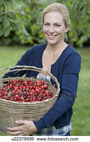 Stock Photo - Woman carrying basket of cherries. Fotosearch