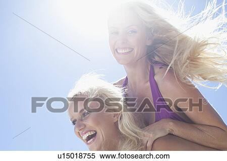 Stock Photography - Woman carrying friend piggyback. Fotosearch