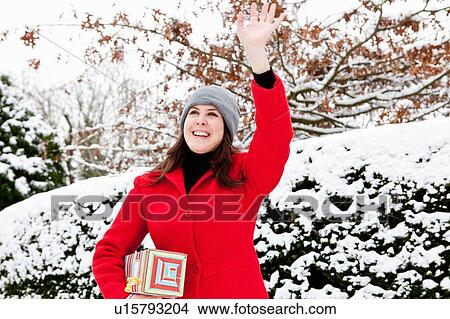 Picture - Woman carrying wrapped gift in snow. Fotosearch