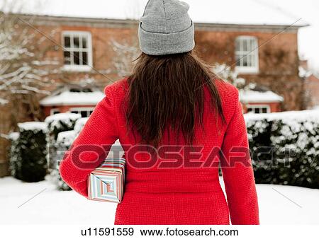Woman carrying wrapped gift in snow View Large Photo Image Stock Photo - Woman carrying wrapped gift in snow. Fotosearch