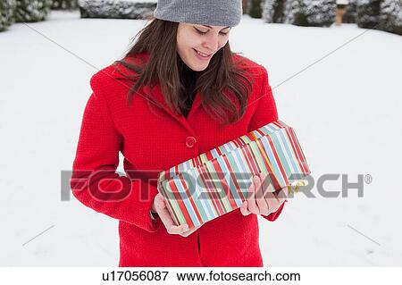 Woman carrying wrapped gift in snow View Large Photo Image Stock Photo - Woman carrying wrapped gift in snow. Fotosearch