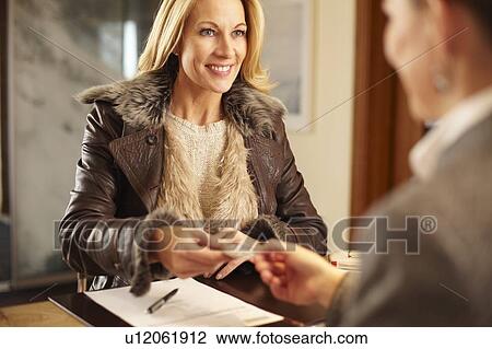 Stock Image - Woman checking in to hotel. Fotosearch