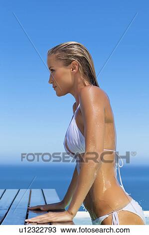 Stock Image - Woman climbing out of swimming pool. Fotosearch