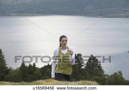 Stock Photograph - Woman climbing rural hill. Fotosearch