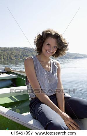 Stock Photo - Woman dangling feet from boat in lake. Fotosearch