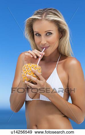 Stock Photo - Woman drinking from pineapple outdoors. Fotosearch