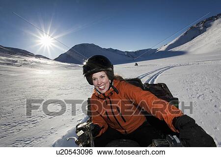 Stock Photograph - Woman driving snowmobile in snowy field. Fotosearch