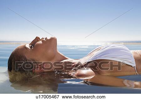 Woman floating in swimming pool View Large Photo Image Stock Photo - Woman floating in swimming pool. Fotosearch