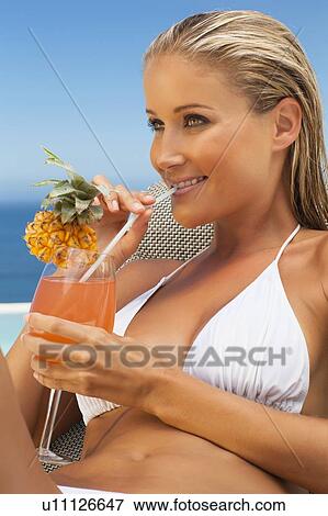 Stock Photo - Woman having drink in lawn chair by pool. Fotosearch