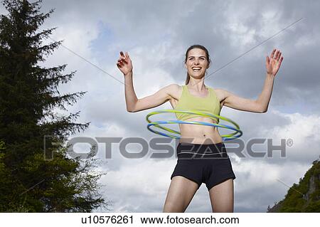Stock Image - Woman hula hooping outdoors. Fotosearch