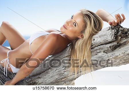Stock Image - Woman in bikini laying on log. Fotosearch