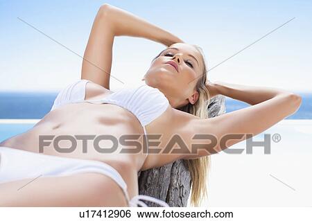 Stock Photograph - Woman in bikini laying on log. Fotosearch