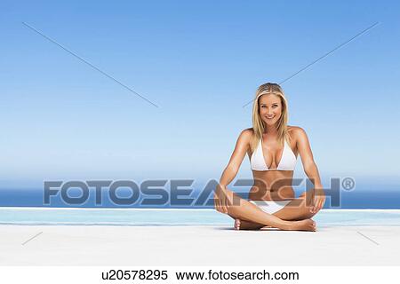Stock Photography - Woman in bikini meditating by pool. Fotosearch