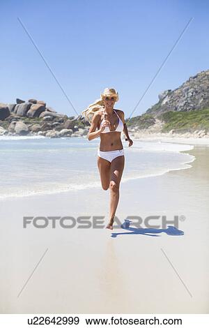 Stock Photo - Woman in bikini running on beach. Fotosearch
