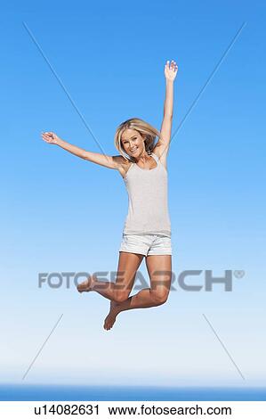 Stock Image - Woman jumping for joy outdoors. Fotosearch