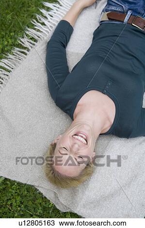 Woman laughing on blanket in grass View Large Photo Image Stock Image - Woman laughing on blanket in grass. Fotosearch