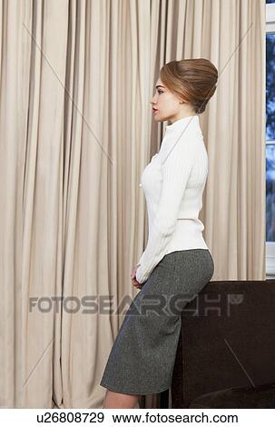 Stock Photo - Woman leaning on couch in living room. Fotosearch