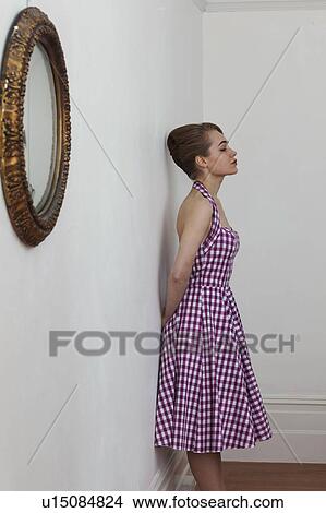 Picture - Woman leaning on wall in hallway. Fotosearch